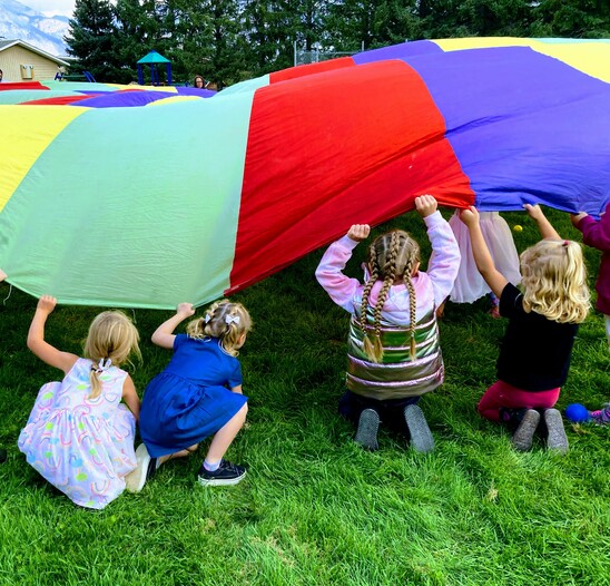 Students play with a parachute on the grass